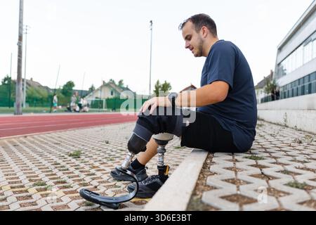 Young man replacing transtibial prostheses for daily walking and sporting activities, taking off a running blade and putting on an artificial leg with Stock Photo
