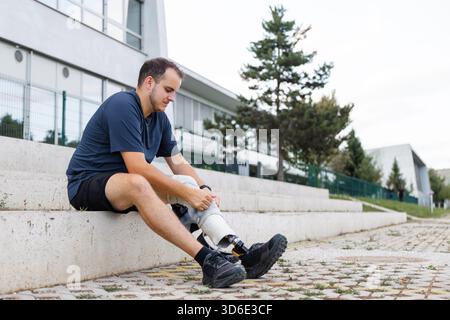 Young man replacing transtibial prostheses for daily walking and sporting activities, taking off a running blade and putting on an artificial leg with Stock Photo