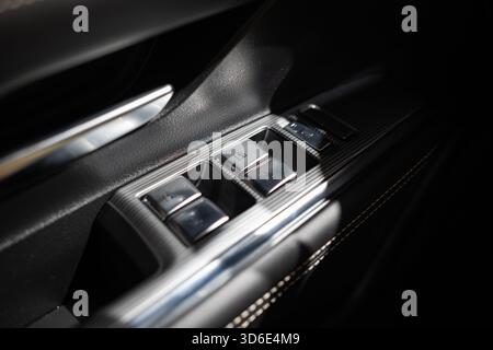 New, modern car electric window metal buttons on the driver side door panel. Close up shot, no people Stock Photo