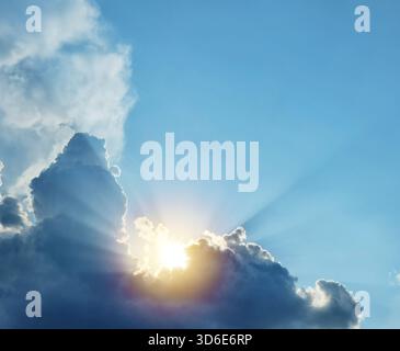 The sun and sun rays appearing from behind a great fluffy cloud. Stock Photo