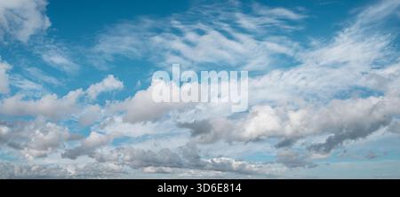 Sky panorama filled with a variety of clouds, from fluffy cumulus to wispy cirrus, stretches across the horizon on a bright and clear day. Stock Photo