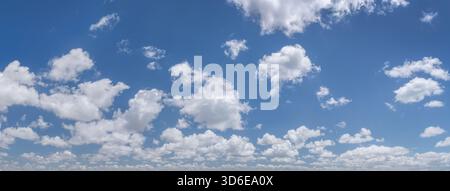 Panorama of skyscape with puffy, white cumulus clouds in the blue sky. Stock Photo