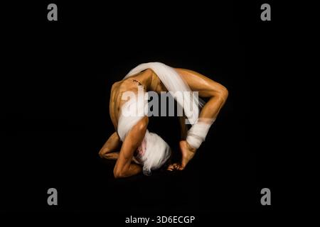 Color portrait of a male ballet dancer performing an elegant classical pose in a studio setting. Stock Photo