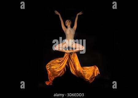 Color portrait of a female ballet dancer performing an elegant classical pose in a studio. Stock Photo