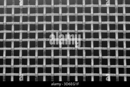 White synthetic mesh grid showing tight woven texture and repeating geometric cells against a dark background, close-up detail. Photography, not gener Stock Photo