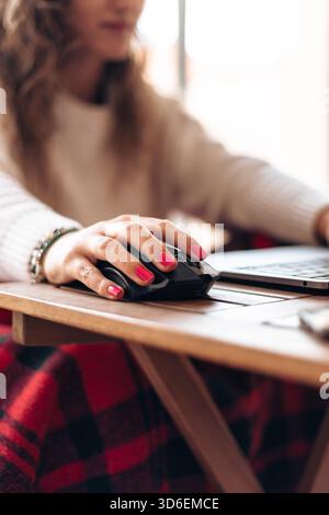 Anonymous of young female freelancer sitting at table with laptop and typing information while working on new project in modern home Stock Photo