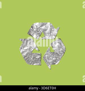 A conceptual image depicting the recycle symbol crafted from crumpled aluminum foil, isolated on a green background, representing recycling and enviro Stock Photo