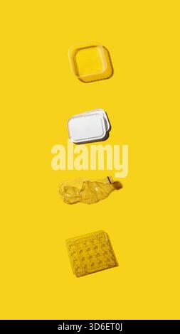 An assortment of packaging types including a plastic container, a crushed bottle and egg carton on a yellow background, suggesting recycling themes. Stock Photo