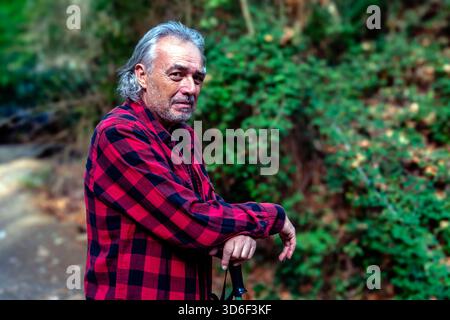 Senior man hiking in nature wearing plaid shirt Stock Photo