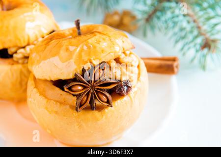 Christmas baked apples stuffed with dried fruit, nuts, cinnamon, anise and honey on white plate close up Stock Photo