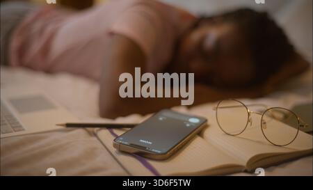 Tired sleeping African American woman female girl student businesswoman asleep napping nap sleep don't hear mobile phone calling receiving incoming Stock Photo