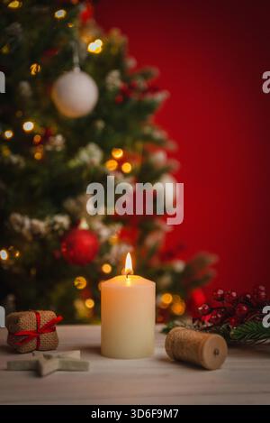 Warm Christmas candle burning in a cozy holiday setting with soft lights, ornaments and festive decor creating a peaceful seasonal atmosphere Stock Photo