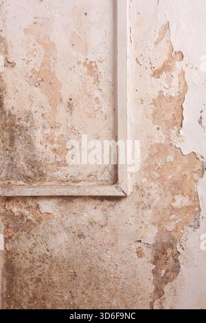 close-up of peeling paint on old wall, damaged plaster with reddish-brown stains, worn architectural texture, background of decay and water damage Stock Photo