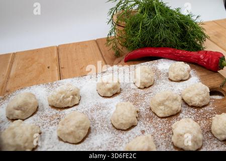 Raw meatballs on wooden board with flour and fresh herbs for homemade cooking Stock Photo