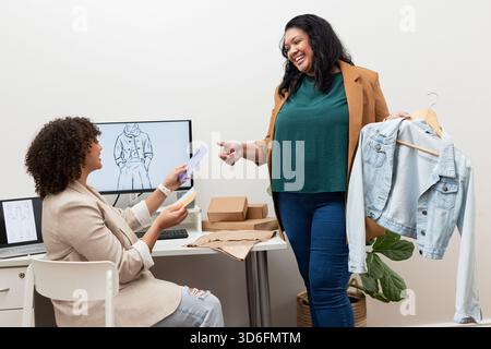 Diverse female colleagues collaborating on design in studio with color swatches and denim jacket Stock Photo