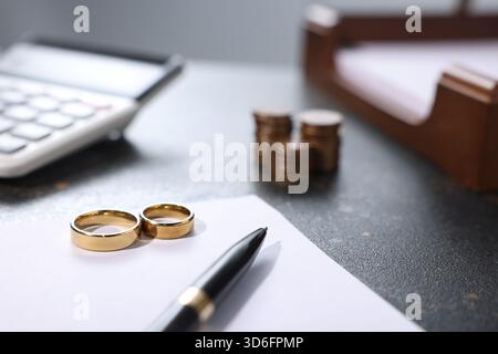 Alimony. Coins, wedding rings, calculator, documents and pen on dark table, closeup Stock Photo