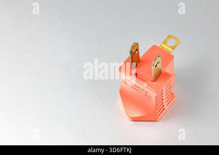Orange plugs adapters for NEMA plug type B convert to type A with grounded contact isolated on white background. Stock Photo