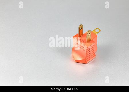 Orange plugs adapters for NEMA plug type B convert to type A with grounded contact isolated on white background. Stock Photo
