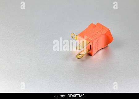 Orange plugs adapters for NEMA plug type B convert to type A with grounded contact isolated on white background. Stock Photo