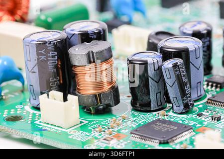 Electromagnetic components produced from copper element and many of capacitors on electronic circuit. Stock Photo