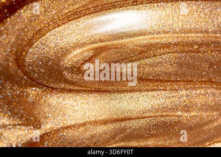 Texture background with golden shimmering cosmetic body spray or gel. Glowing backdrop. Stock Photo