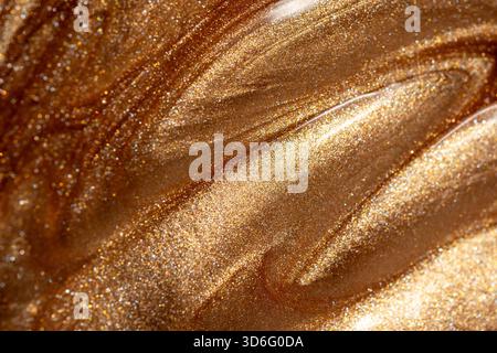Glowing golden shimmering cosmetic texture of gel or body spray. Background texture for backdrops or mapping. Stock Photo