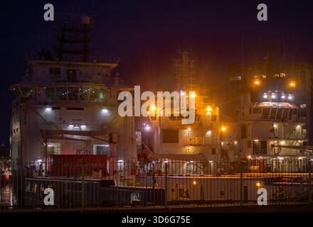 Aberdeen, Scotland – 27th February 2025: Off shore supply ships, or oil supply vessels at night in Aberdeen harbour, ready to return to the North sea. Stock Photo