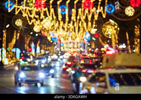 Abstract defocused urban background of night traffic jam with glowing Christmas decorations, bokeh lights and busy city atmosphere. Stock Photo