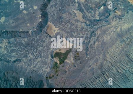 Top-down aerial view of a vast, desolate industrial spoil heap or slag dump. Abstract geomorphic pattern showing layered blue-gray textures, reflecting environmental pollution and damage. Stock Photo