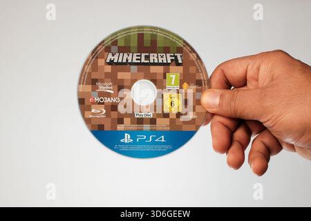Hand holding a PlayStation 4 Blu-ray disc of the highly popular sandbox game, Minecraft. Stock Photo
