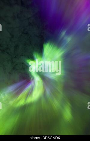 View of vibrant streaks of green and purple dance in a blurred spectacle, creating an ethereal ambiance, Henningsvaer, Nordland, Norway. Stock Photo