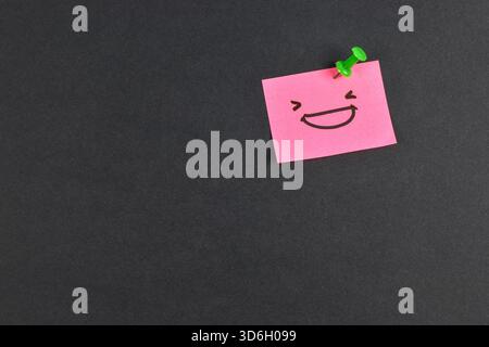 Yellow and pink sticky notes with smiley faces on black background, expressing emotion and contrast through minimal design and color. Stock Photo