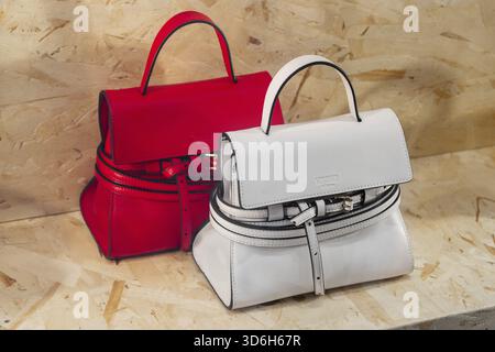 Milan, Italy - April, 12, 2025: Moschino mini handbags in red and white leather on wooden background. Front view, fashion accessories in retail displa Stock Photo