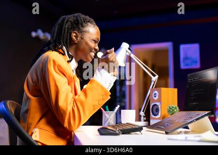 Happy developer at laptop programming, exuberating after writing lines of code, using development tools. Ecstatic woman in home office pleased after finishing debugging software on notebook Stock Photo