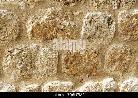 Old beige stone wall background texture close up. Old castle wall surface, antique natural stonewall Stock Photo
