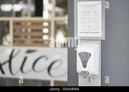 Milan, Italy - May, 27, 2020: Hand sanitizer machine in public place near the wall at the entrance to shopping center or grocery store. Automatic disp Stock Photo