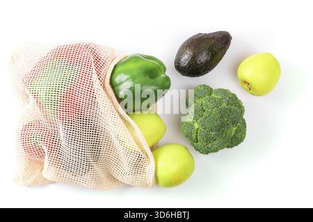 Assorted fresh produce including green apples, bell peppers, avocado, and broccoli in an eco-friendly mesh bag on a white background, emphasizing heal Stock Photo
