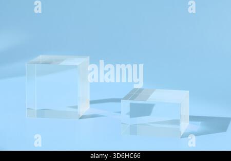 Pedestal podium display glass cubes on blue with shadow and reflection, block platform, transparent geometric stand for cosmetics, minimal mockup. Acr Stock Photo