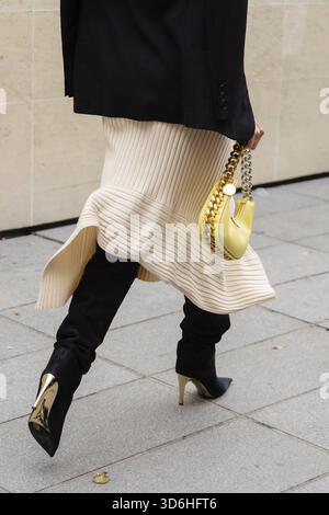 Paris, France - October, 3, 2022: woman wears wrap front ribbed cotton jersey dress, black suede pointed heels knees boots, high boots, gold chain han Stock Photo
