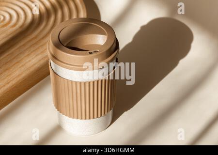 Reusable cup, biodegradable travel plastic coffee mug for take away. Sustainable bamboo eco friendly cup on natural shadow beige background. Zero wast Stock Photo