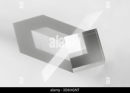Glass transparent cube with sun reflection, geometric stand for cosmetic, light and shadow on white. Physics refraction effect, translucent prism. Acr Stock Photo