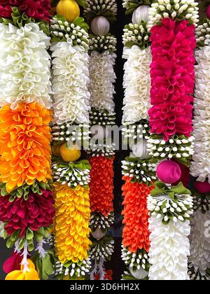 Colorful hanging garlands made of artificial flowers in vibrant hues arranged vertically for traditional decoration Stock Photo