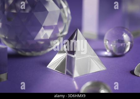 Crystal prism refracting light, magic crystals and pyramid, sphere and cube on purple background. Spiritual healing crystal practice. Feng Shui, good Stock Photo