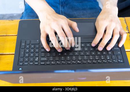 Person's hands actively typing on a laptop keyboard, working or studying from home, engaging with technology Stock Photo