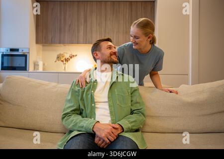Happy smiley married young couple in cozy living room enjoying bonding and peaceful time at home. Stock Photo