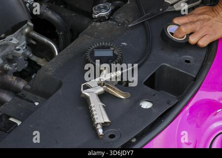Focused mechanic performs car diagnostic and repair with pressure gauge tool. man hand holds tape for maintenance on vehicle engine in an auto service Stock Photo