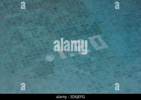 Calm blue water surface of swimming pool with mosaic tile bottom. depth marker number indicating measurement for safety creates serene and peaceful fe Stock Photo