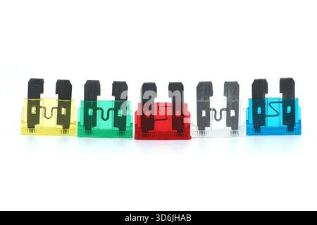 A row of colorful, transparent blade fuses with black pins, arranged in yellow, green, red, clear, and blue. Perfect for illustrating wiring, electron Stock Photo