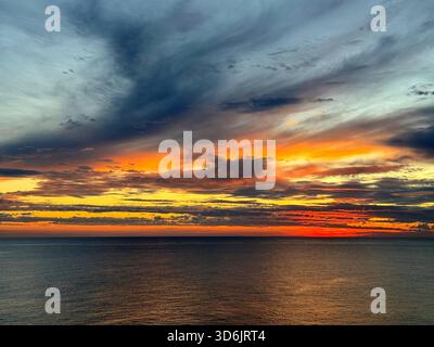 Dramatic sunset sky clouds above dark sea at night Stock Photo