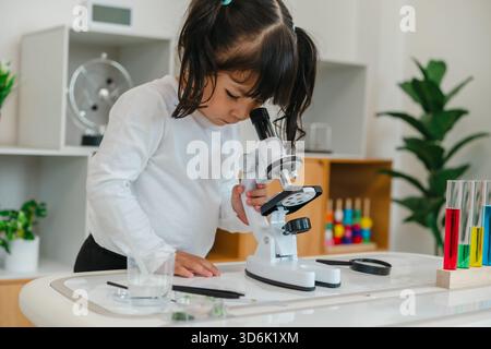 toddler girl scientist looking through a microscope. learning science Stock Photo